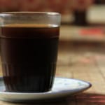 Ilustrasi secangkir kopi hitam di atas meja kayu pada pagi hari